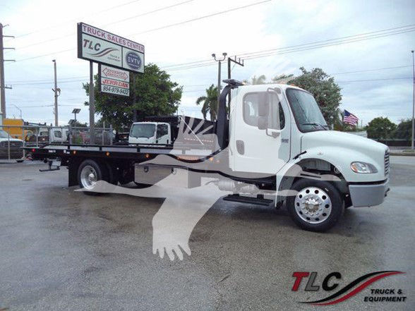 Freightliner Business Class M2 106 tow truck in a dealership lot with TLC logo watermark. Visible text on signage includes TLC Truck & Equipment and signboards.