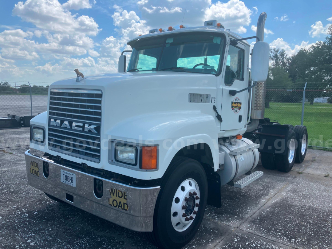Mack CHN613 cab and chassis truck with white exterior, front chrome bumper, large grille, and dual rear axles. Visible labels include V6 badge on door and 'WIDE LOAD' markings on bumper.