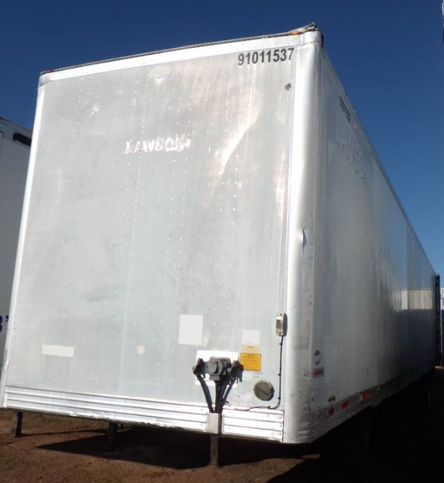 Composite utility trailer showing rear door with hitch and identification number 91011537 at top edge; metal silver exterior, vertical rivets, and small warning sticker near hitch.