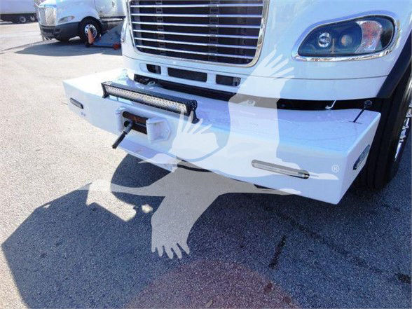 Front view of a Freightliner M2 106 truck showing a heavy-duty white front bumper with a winch plate and bumper guards. Grille and headlight on right, tow hitch visible.
