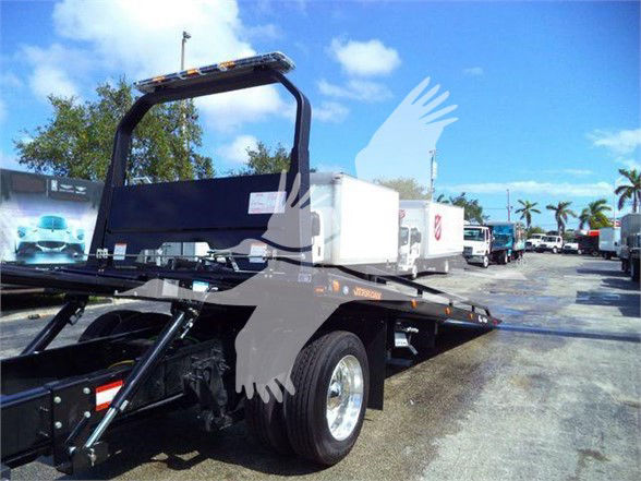 Tow truck chassis with flatbed and hydraulic ramp, International MV model, new unit, stock MV607RED in a dealership lot.