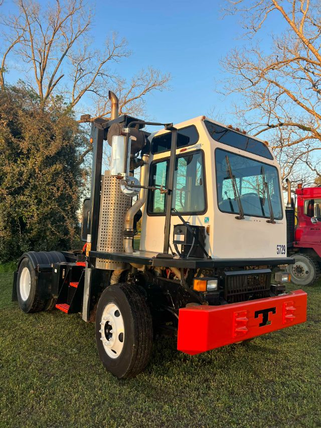 Rear three-quarter view of a white 2014 Tico ProSpotter yard truck with a bright red front bumper, large black tires, and a cab with windows and exhaust stack.