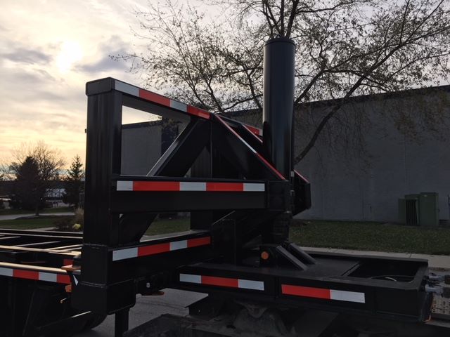 Trailer chassis showing a vertical exhaust/stack and folding gooseneck with black frame and red-white reflective tape. 2003 Wabash TIPPER trailer in a yard.