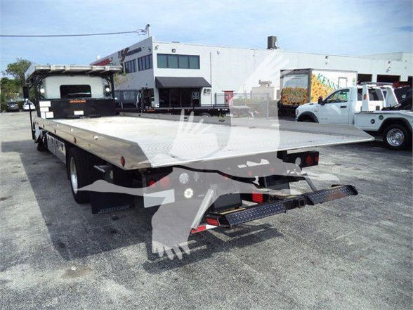 Flatbed tow truck with KW4CARCARRIER stock number, Kenworth T370 in background, aluminum flatbed with rear ramps and warning lights.