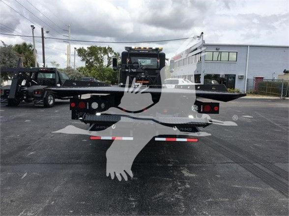 Peterbilt 337 tow truck rear view with flatbed in a dealership lot.
