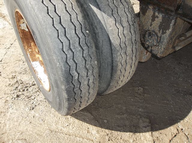 Two tires on a Wilson flatbed trailer showing tread and wheel hubs.