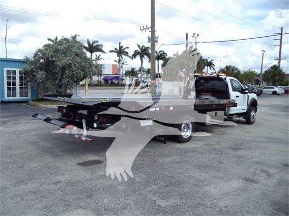 Ford F-550 tow truck with flatbed and rear equipment showing in-service components and a white cab.