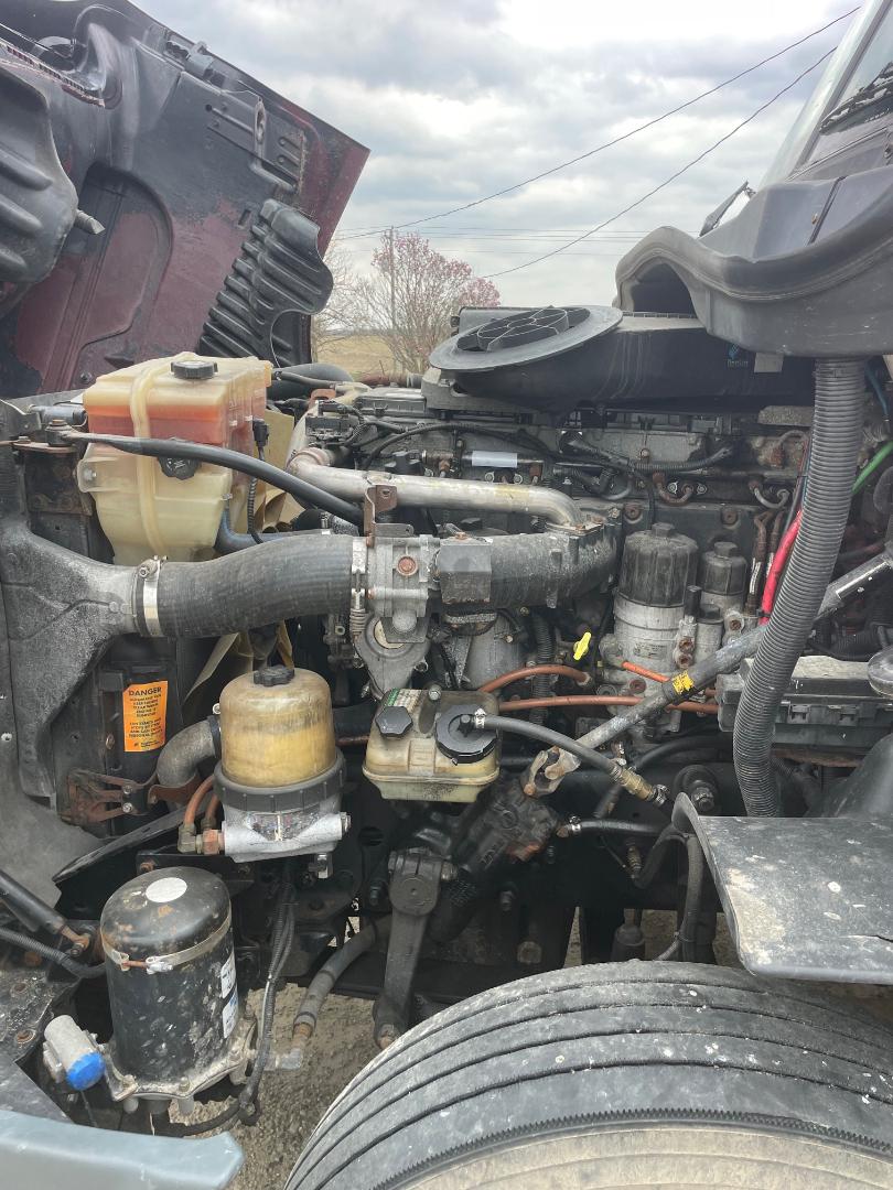 Truck engine bay of a 2014 Freightliner Cascadia 125 with visible coolant reservoir, hoses, air dryer, and various components.