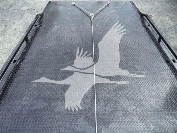Flatbed or platform with diamond plate pattern showing two birds in flight graphic and a central rope tie-down. No legible labels or controls visible.