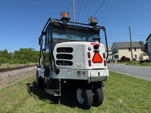 Elgin Pelican NP sweeper truck rear view showing white body, units, rear triangle hitch, and orange warning beacon lights.