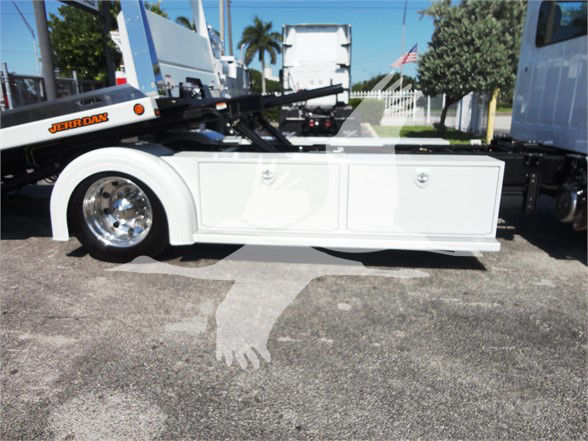 Low-angle side view of a white 2022 Hino 268A tow truck chassis with side storage compartments.