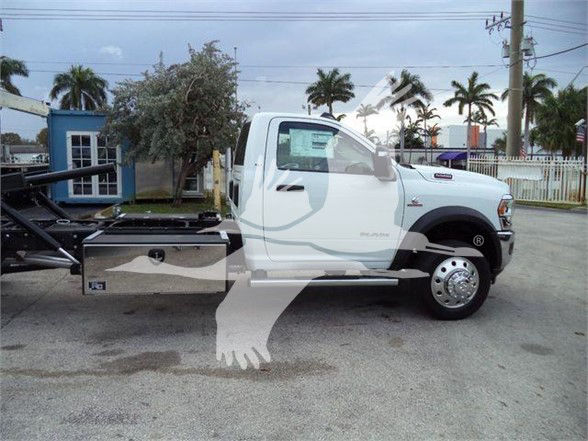 Ram 5500 cab chassis tow truck with white body and extended aluminum toolbox on side, displaying VIN and stock number in a dealership lot.