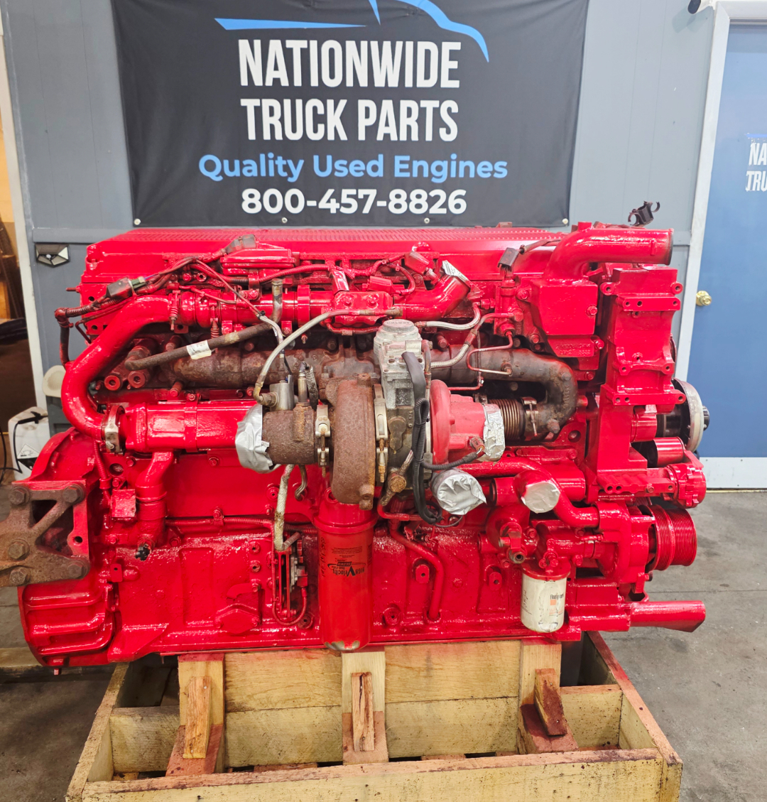 Isx15 engine bay with bright red painted diesel engine and turbocharger, mounted on wooden pallet; various hoses and components labeled.