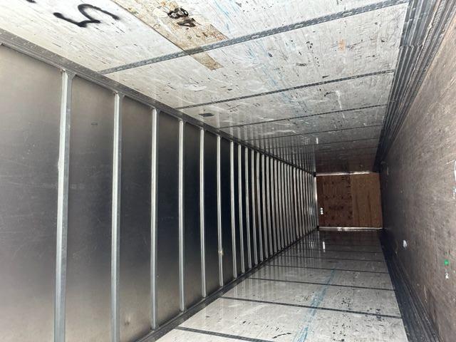 Interior of a 2007 Stoughton dry van trailer showing aluminum ceiling ribs, wall liner with graffiti, and a wooden bulkhead at far end.