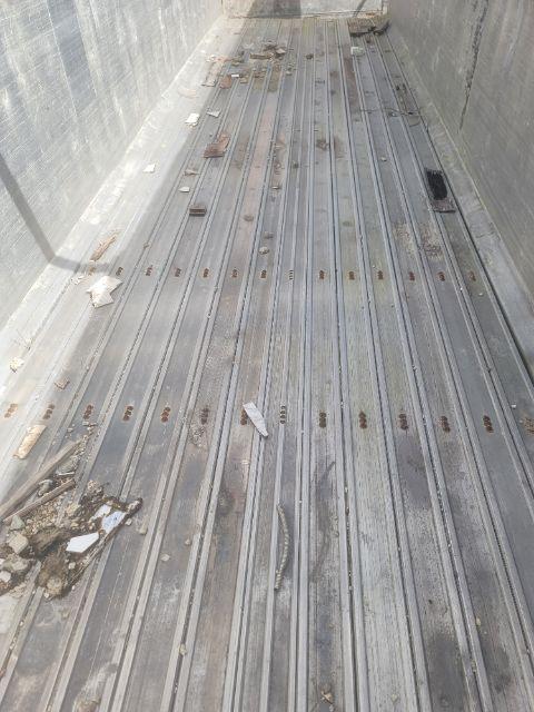 Trailer bed interior showing metal floor with ribbed texture and scattered debris.
