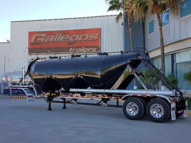 2019 Gallegos Steel 1040cuft Pneumatic trailer in front of Gallegos trailers building, black cylindrical tanker with multiple cones, tandem axle wheels, Side rails and hoses visible.
