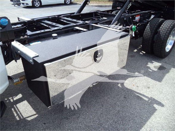 Truck chassis with large rectangular toolbox mounted behind cab and dual rear wheels visible.
