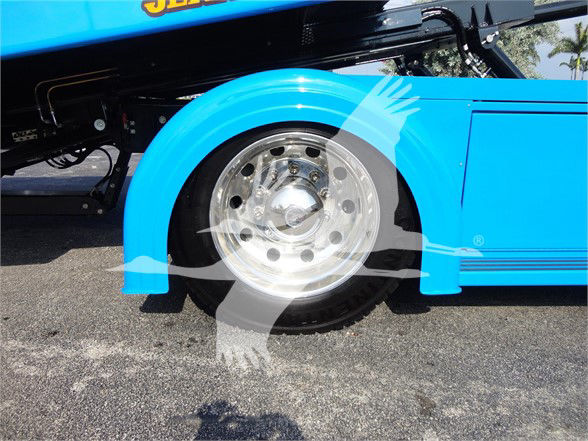 Front wheel area of a blue 2022 Peterbilt 337 tow truck showing polished rim and fender.