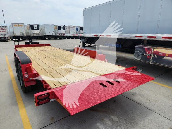 Behnke flatbed trailer showing wooden deck, red steel ramp end, and dual wheels in a truck yard.
