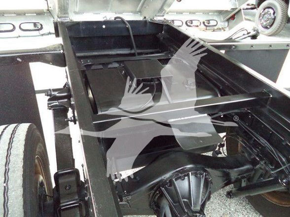Truck chassis with empty rear dump bed showing frame rails and differential housing.