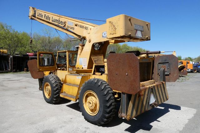 Grove RT58 crane truck in service showing arm boom and counterweights with rust patches and heavy tires.