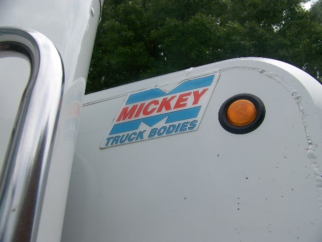 Truck cab area with Mickey Truck Bodies badge on white surface and an orange circular light, Volvo? Peterbilt 335 not visible.