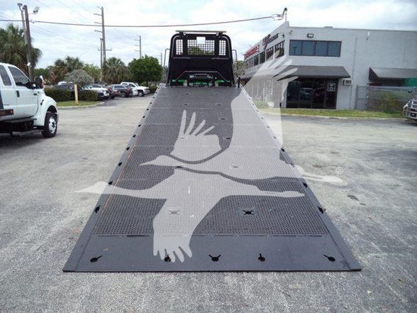 2016 Peterbilt 348 tow truck bed with foldable ramp; VIN visible in listing; flatbed with perforated steel surface and headboard in background.