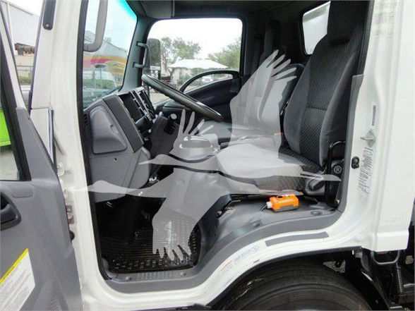 Isuzu NQR truck cab interior showing driver seat, steering wheel, and passenger seat with floor mat; orange tool/handle on center console.