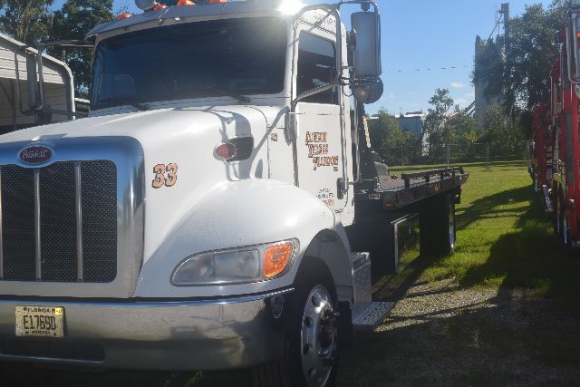 Peterbilt 337 rollback truck side view showing front grille with 33 badge and bumper, white cab, and flatbed equipment.