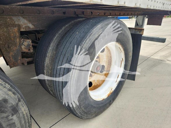 Great Dane trailer wheel showing dual tire and rim with rusted hub; watermark of a crane logo overlay.