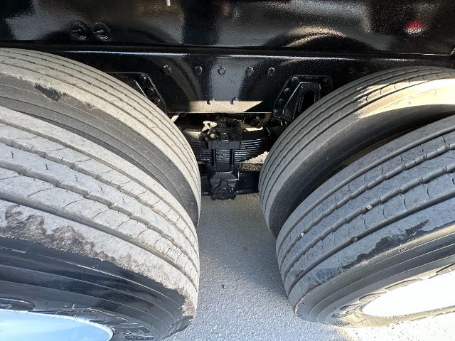 Dual rear axles and suspension undercarriage of a truck with large tires and differential visible between the axles.