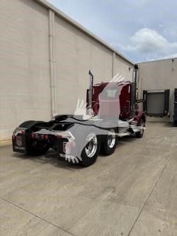 Kenworth T880 truck in a yard with red chassis and triple axles visible. No text readable on the image surface.