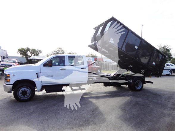 Chevrolet Silverado 5500HD dump bed, white cab, side view with dump box raised. Visible text on truck may include model badges but not clearly legible.
