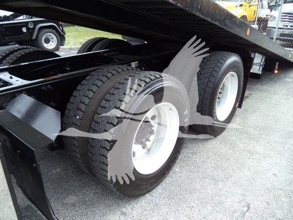Peterbilt 348 dump trailer dual rear axles with heavy-duty tires and white rims under a flatbed trailer.