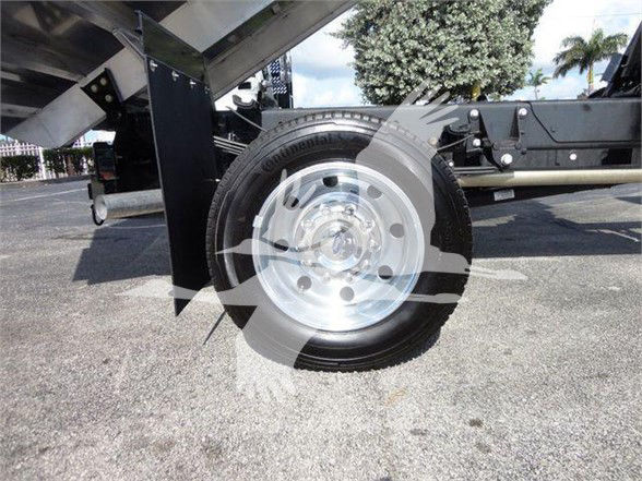 Flatbed trailer hitch/front wheel of a Ford F-550 dump truck with a shiny steel wheel and black frame components visible.