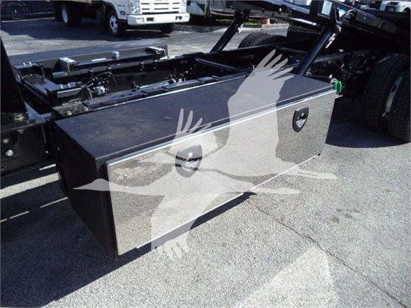 Truck flatbed chassis showing a large metal toolbox on the side, with chrome handles and a green valve visible in the background.