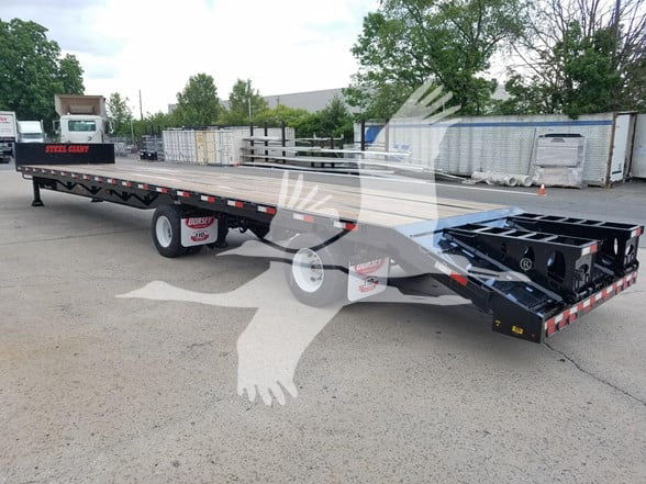 Dorsey Steel Dropdeck Beavertail trailer in a yard showing long flatbed with black frame and beavertail rear, tires, and various equipment areas.