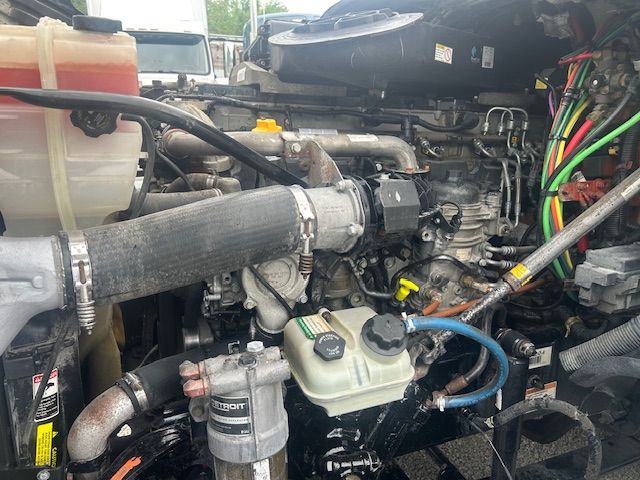 Techno-graphic engine bay of a 2019 Freightliner Cascadia 125 showing coolant reservoir, hoses, belts, and engine components