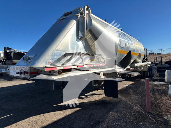 Mac trailer with a large aluminum cylindrical tank, rear view showing hitch, support legs, and safety markings.