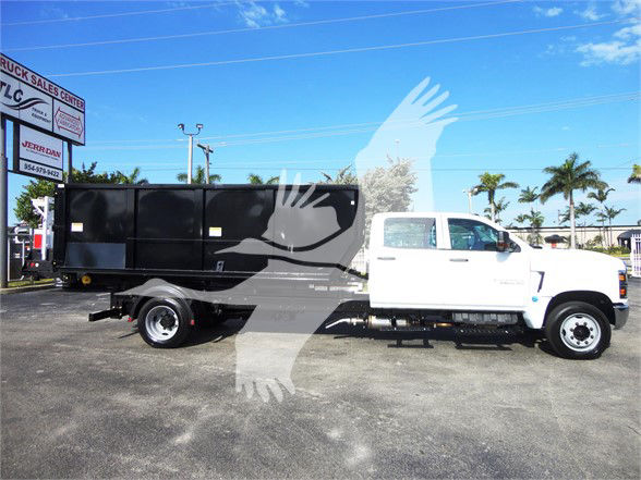 2023 Chevrolet SILVERADO 5500HD dump truck with white cab and black dump body in lot. Stock J82601.