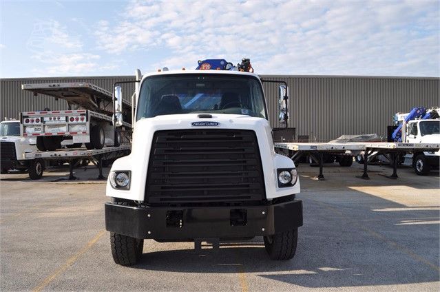 Knuckle boom truck front view showing large grille and bumper under a clear sky.