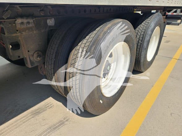 Trailer wheels showing dual tires and white rims on a Wabash trailer with visible steel undercarriage. No legible branding or model text visible in this crop.