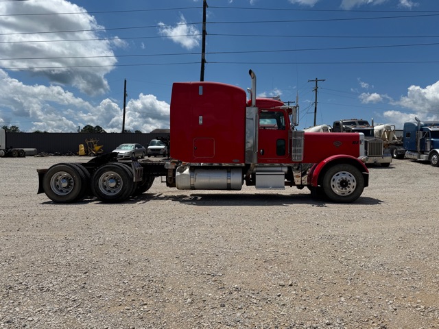 Red 2007 Peterbilt 379 tractor in side profile with sleeper cab, single-frame chassis, large fuel tanks, gravel lot.