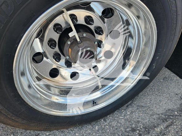 Wheel of a trailer showing a polished chrome rim with multiple circular holes and a central hub.