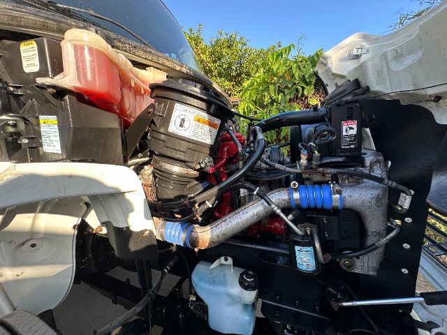 Freightliner M2 engine bay showing air intake, coolant reservoir, intercooler hoses, and hydraulic lines.
