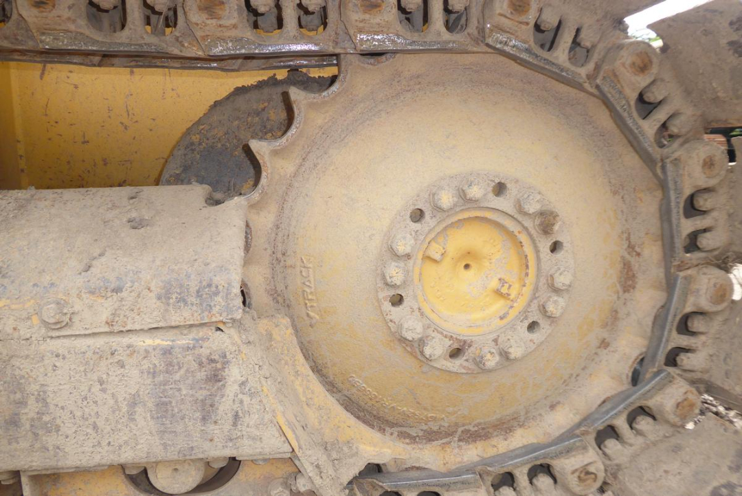 John Deere 650HLT track drive sprocket and track assembly with mud and dirt accumulation.