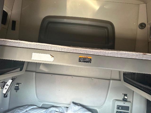 Interior of a sleeper cab area on a 2017 International Prostar showing storage area and a small label on a metal rail.
