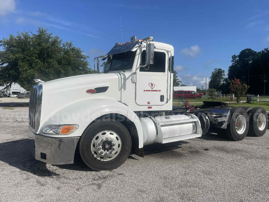 Peterbilt 386 cab and chassis in white, side view showing front grille, chrome bumper, single front wheel, fuel tanks, and dual rear axles with aluminum wheels.