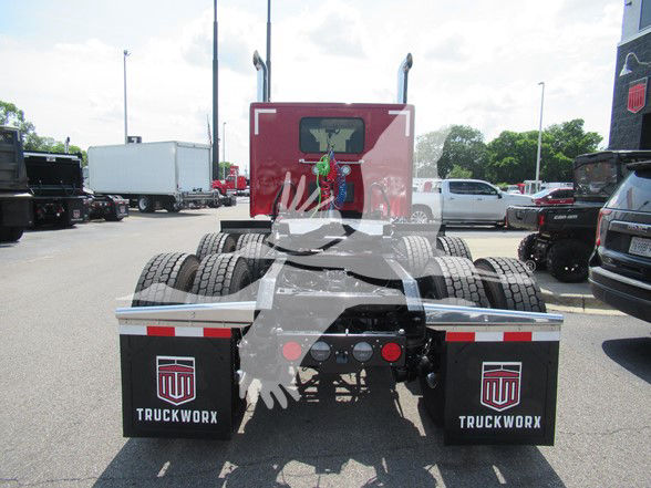 Rear view of a new Kenworth W990 tractor with dual rear axles and black mudflaps that read 'TRUCKWORX'.