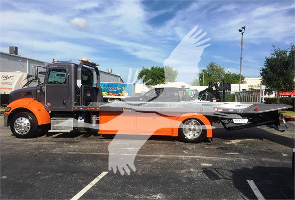 2022 Peterbilt 337 tow truck in a lot, orange and gray color scheme with a long flatbed trailer, cab front left, stock number J47166.